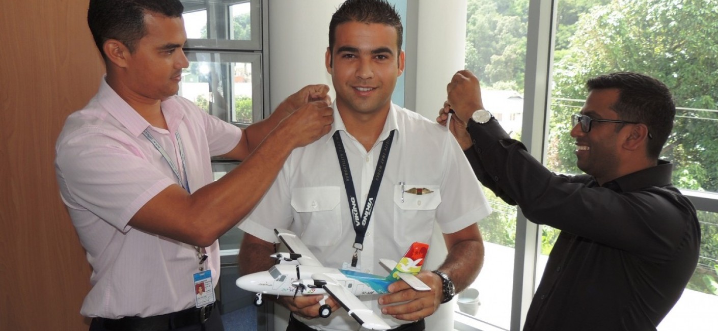 Captain Allen Dubignon, Chief Pilot Domestic (left), and Manoj Papa, Air Seychelles’ Chief Executive Officer (right), fasten Captain Mein’s commander’s bars